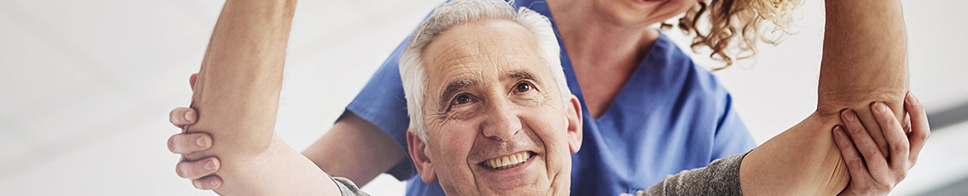 Senior man doing physical therapy exercises with help of caregiver