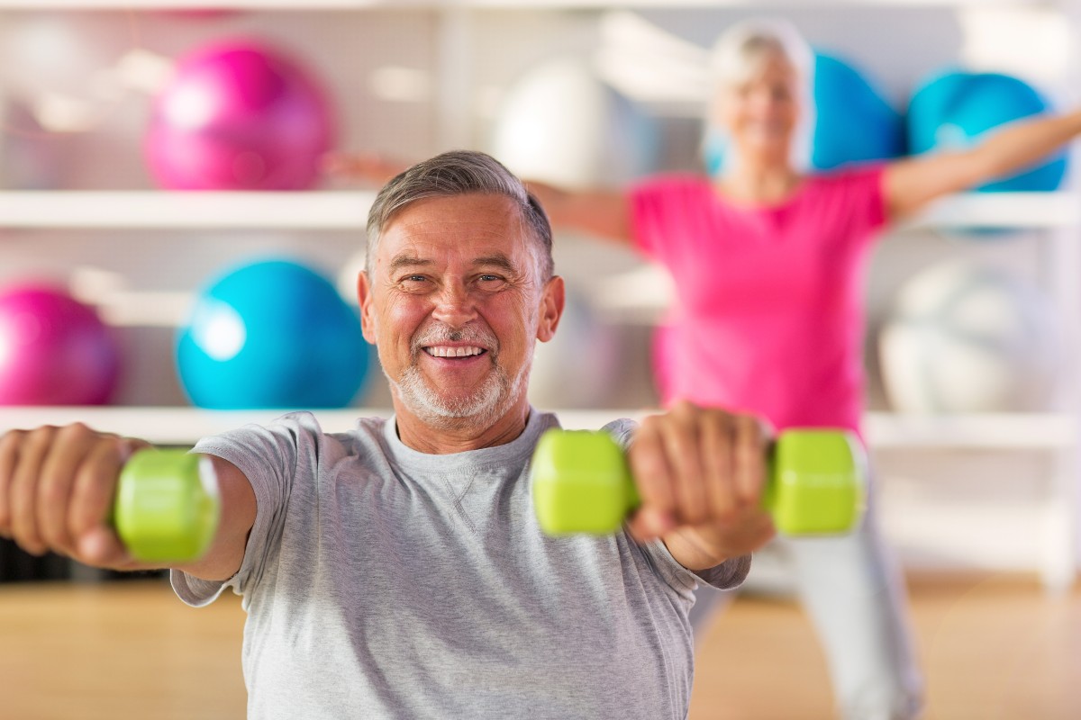 senior man and woman exercising with weights at a retirement community