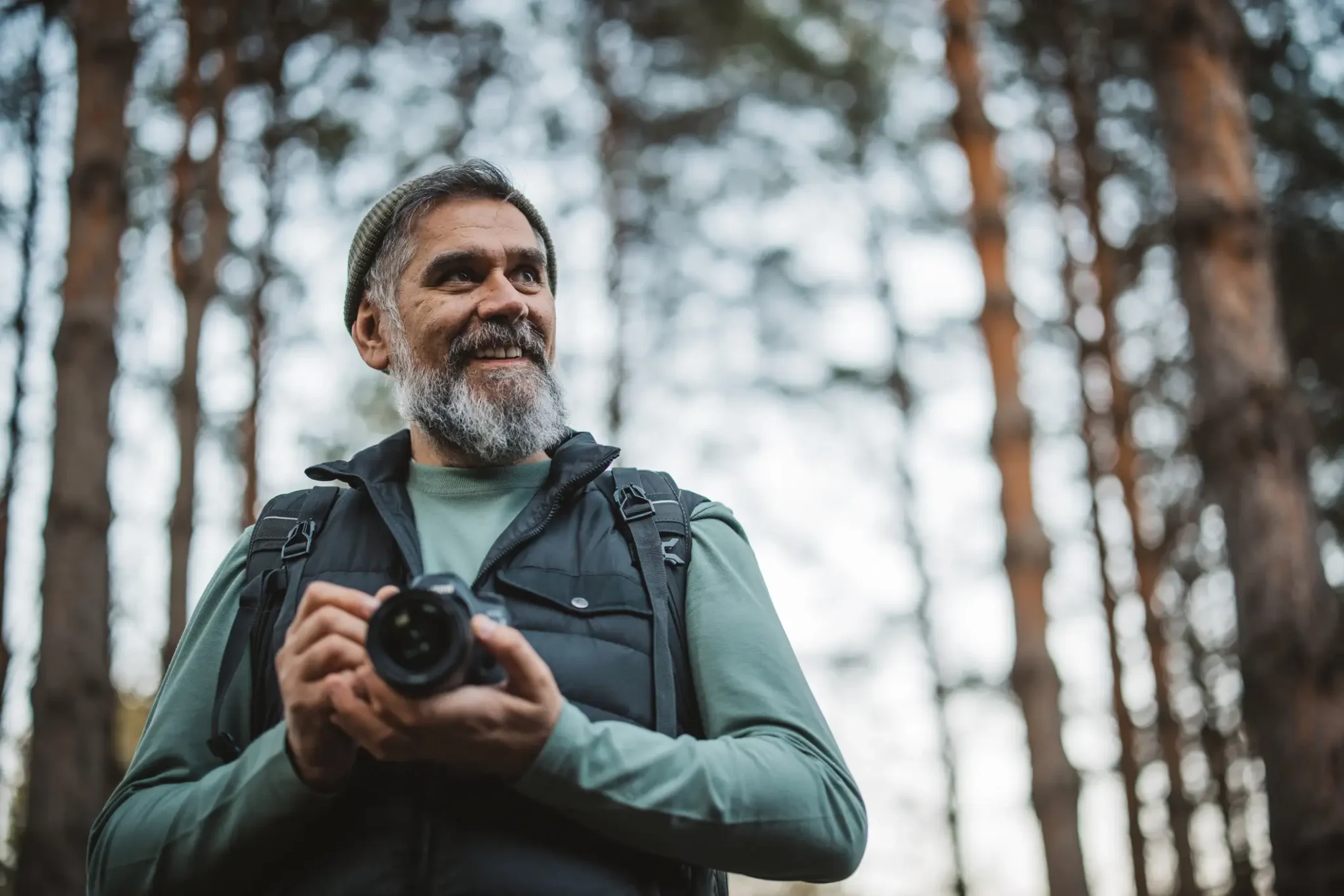 Senior man with an SLR camera taking photographs in the woods