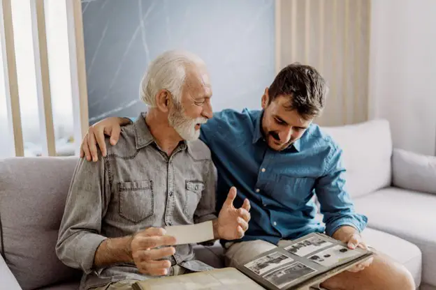 senior man looking at old photos with his adult son