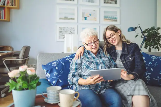 senior woman looking at a tablet with her adult daughter