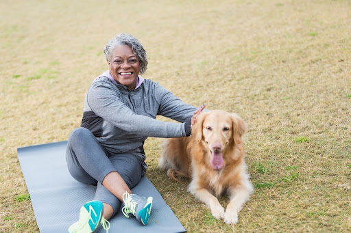 senior woman outside with her dog on a yoga mat